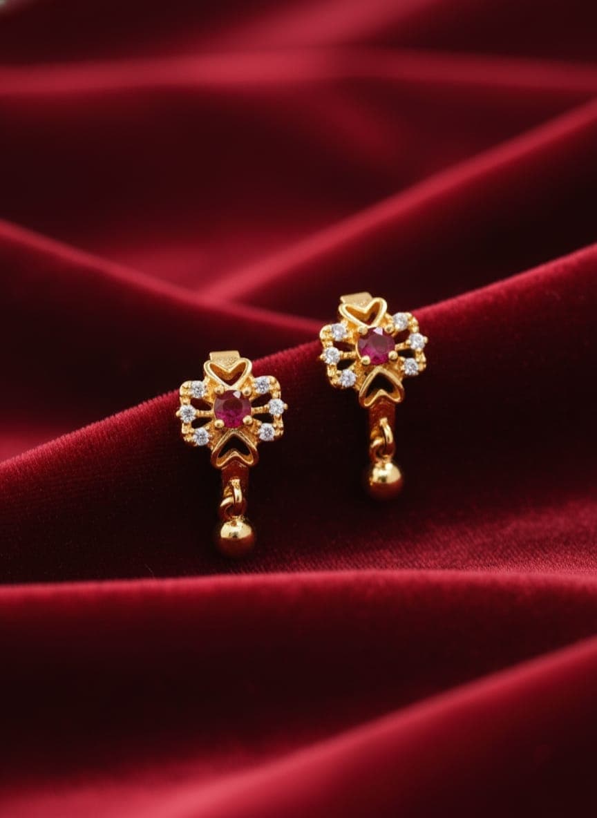 A delicate gold-plated earring featuring an elegant flower design. It is studded with a central red stone, surrounded by sparkling stones. It features a delicate gold ball pendant. Clip-Ons (4)