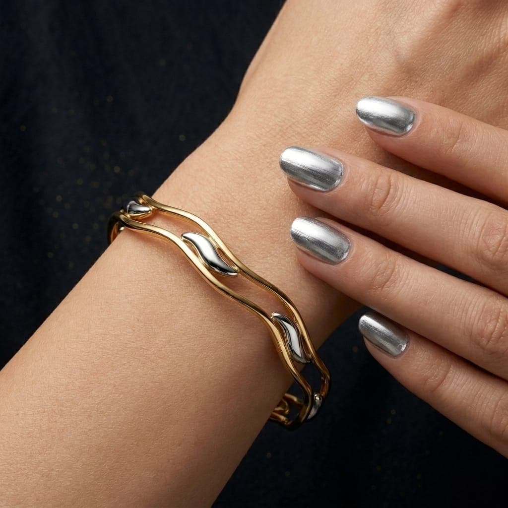 A luxurious bracelet in elegant gold, with a flowing, wavy design that combines the richness of gold with almond-shaped touches of silver. It adds a special charm to your look. Women's Bangles (2)