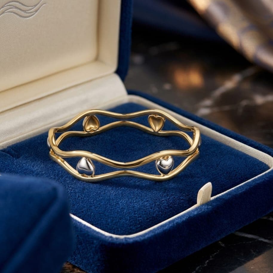 A luxurious, elegant gold-tone bracelet with a double wavy design, adorned with delicate, shimmering silver hearts. A stylish piece that adds a touch of glamour to your look. Women's Bangles (6)
