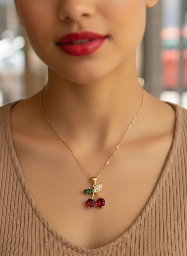 A delicate necklace with a gold-plated chain, featuring a red cherry pendant and sparkling stones - with small, bright green leaves - adjustable to fit your preferred length. Women's Necklaces
