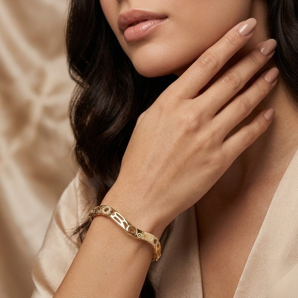 An elegant gold-colored bracelet with an innovative wavy, streamlined design, adorned with oval cutouts and rings studded with charming zircon stones, giving you a luxurious, modern look. Women's Bangles (٣)