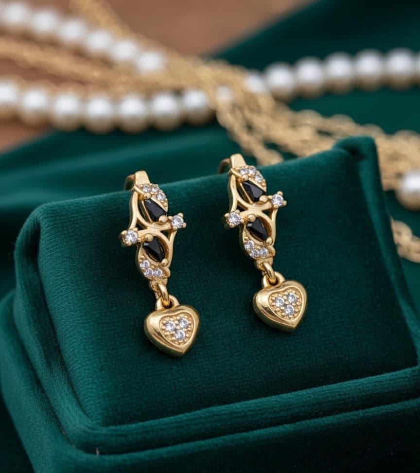 A delicate gold-plated earring with a distinctive design studded with shiny black and white zircon stones, from which hangs an elegant and shiny heart-shaped pendant. Clip-Ons (٦)