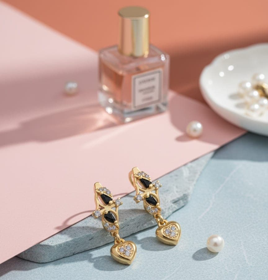 A delicate gold-plated earring with a distinctive design studded with shiny black and white zircon stones, from which hangs an elegant and shiny heart-shaped pendant. Clip-Ons (٧)