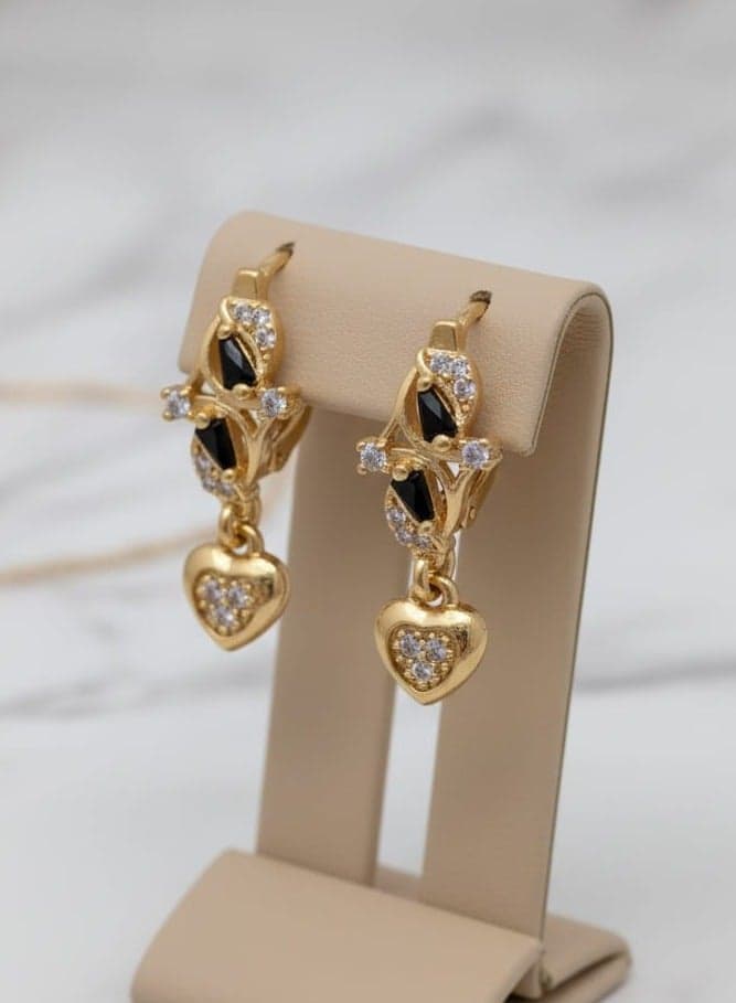 A delicate gold-plated earring with a distinctive design studded with shiny black and white zircon stones, from which hangs an elegant and shiny heart-shaped pendant. Clip-Ons (٢)