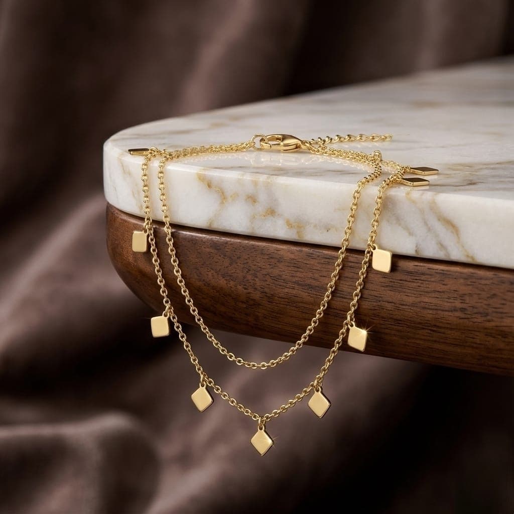 A luxurious anklet in elegant gold, with an attractive double design adorned with delicate geometric diamond-shaped pendants, and an adjustable clasp to fit you, adding charm to your look. (٦)