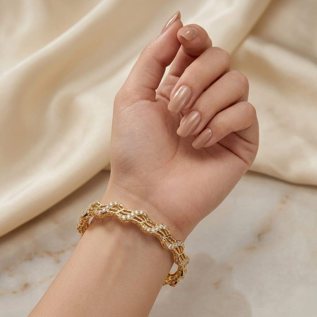 An elegant gold-tone bracelet with a flowing, wavy design that blends luxury and simplicity. Adorned with sparkling zircon stones and delicate engravings, it adds a touch of beauty to your look. Women's Bangles (4)